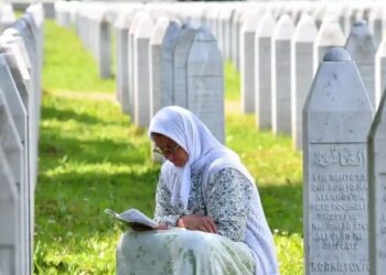 Një grua myslimane nga Bosnja, lutet pranë gurëve të varrit të viktimave të masakrës së Srebrenicës të vitit 1995 (foto: Elvis Barukçiq/AFP/Getty Images)