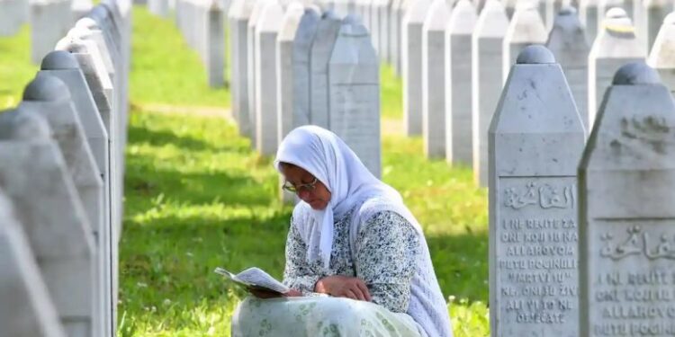 Një grua myslimane nga Bosnja, lutet pranë gurëve të varrit të viktimave të masakrës së Srebrenicës të vitit 1995 (foto: Elvis Barukçiq/AFP/Getty Images)