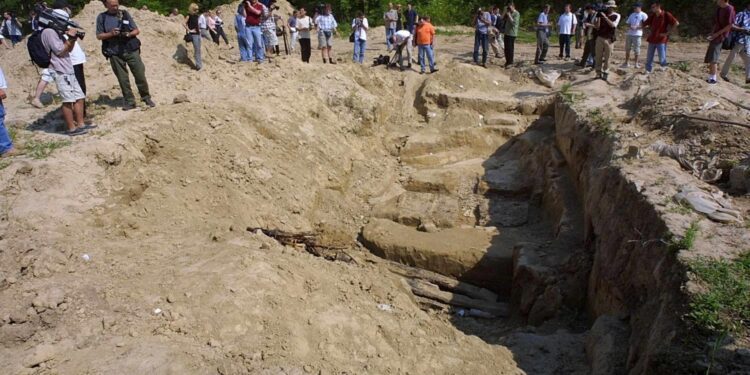 BEL02 - 20010709 - BATAJNICA, SERBI, JUGOSLLAVI: Gazetarët fotografojnë një varr masiv në Batajnicë pranë Beogradit të hënën, më 9 korrik 2001. Në fund të një shtegu të dheut të mbuluar me bimësi që gjarpëron përmes një baze të policisë speciale në periferi të Beogradit, një gropë e hapur shënon vendin ku agjentët e ish-regjimit të Slobodan Millosheviqit fshehën trupat e rreth 36 shqiptarëve të Kosovës gjatë luftës dy vjet më parë. EPA PHOTO EPA/SASA STANKOVIC/AS-ms